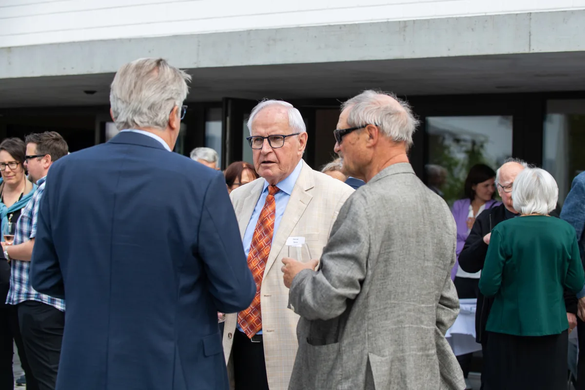 Mehrere Menschen stehen zusammen und reden und lachen. 